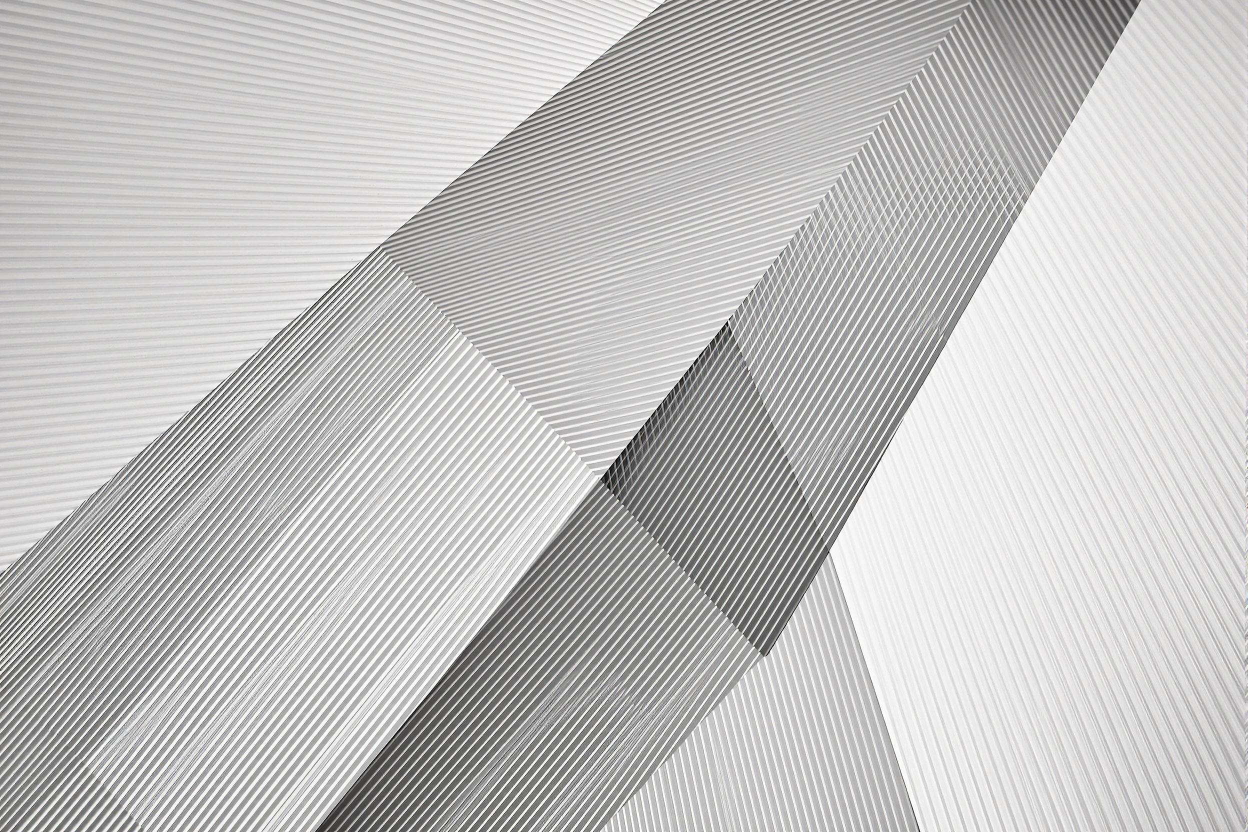 Striking abstract photograph capturing the interplay of architectural lines and geometric shapes. Crisp edges and bold angles create a mesmerizing composition, showcasing the beauty of modern urban design through a minimalist lens.