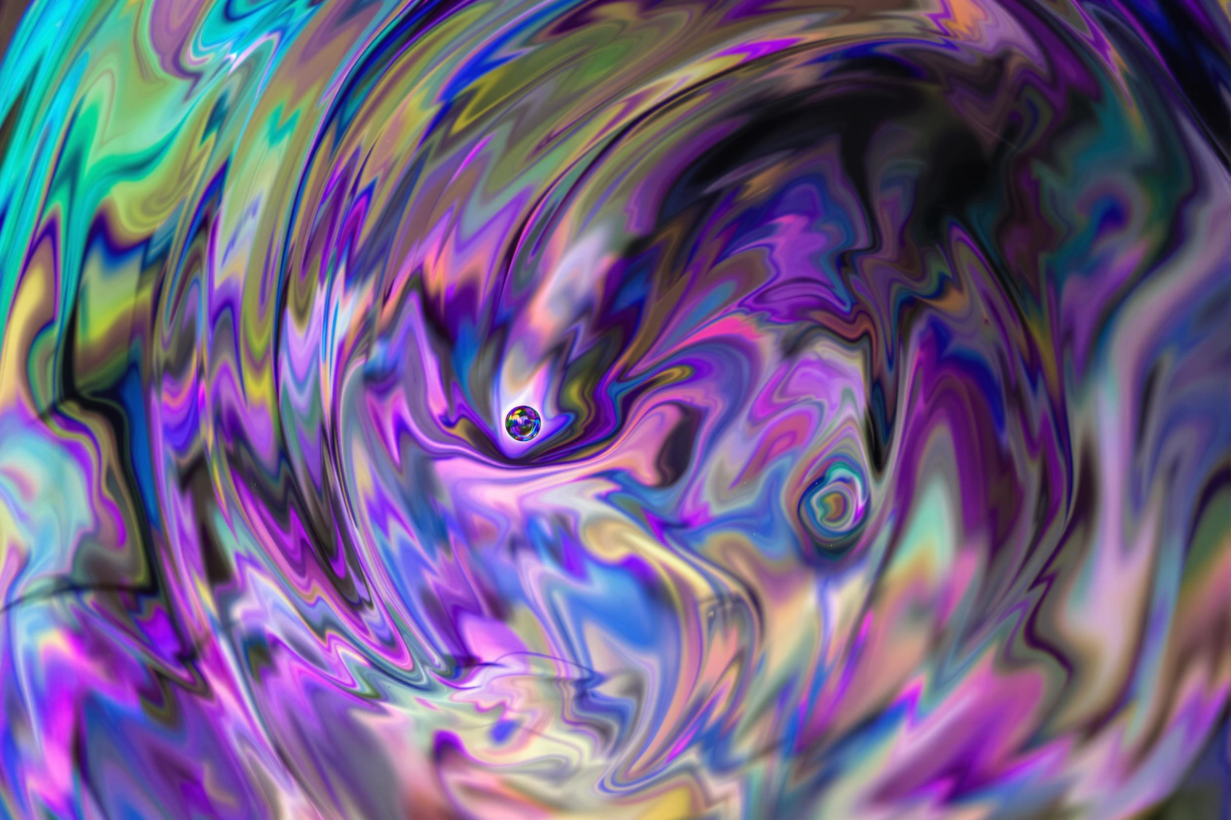 Macro photograph capturing the fleeting beauty of a soap bubble's surface. Swirling patterns of iridescent colors dance across the delicate membrane, creating a mesmerizing abstract composition that explores the interplay of light, tension, and transience.