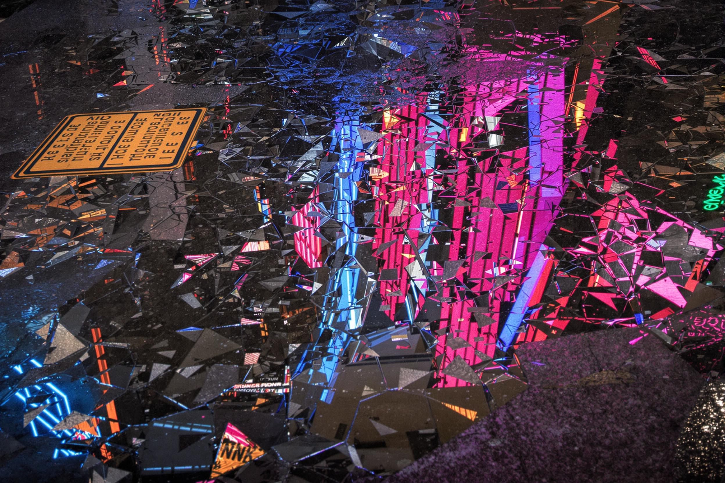 Discover the hidden artistry of city streets in this mesmerizing abstract photograph. A shallow puddle becomes a canvas, reflecting fragmented architecture and neon lights, creating a kaleidoscopic urban landscape that challenges perception.