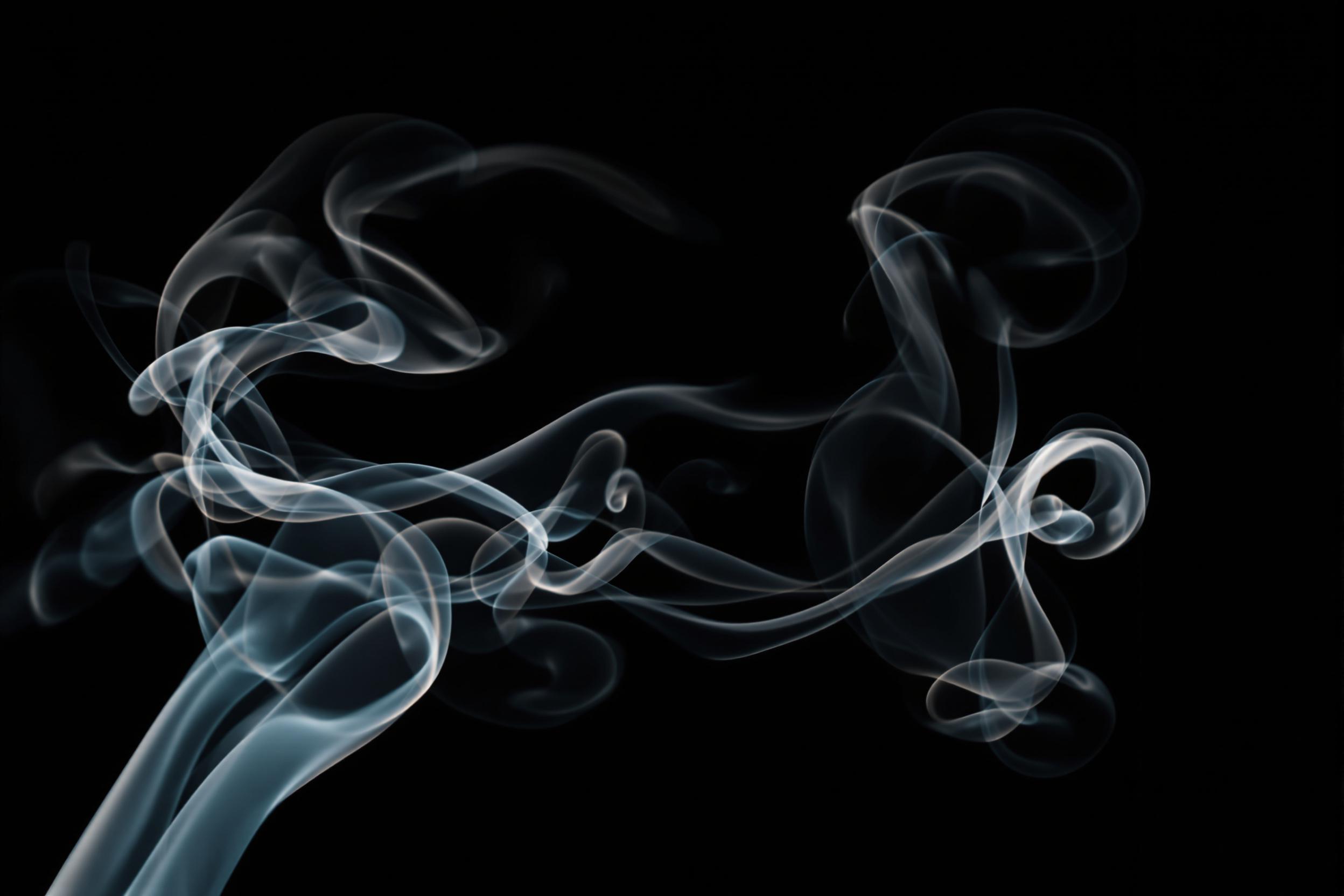 Mesmerizing wisps of smoke dance against a dark background, creating an ethereal abstract composition. Delicate tendrils intertwine, forming graceful curves and spirals that evoke a sense of mystery and elegance. The interplay of light and shadow accentuates the smoke's translucent quality, revealing intricate details and subtle gradients. This captivating image serves as a perfect backdrop for themes of transformation, fluidity, and the ephemeral nature of beauty.