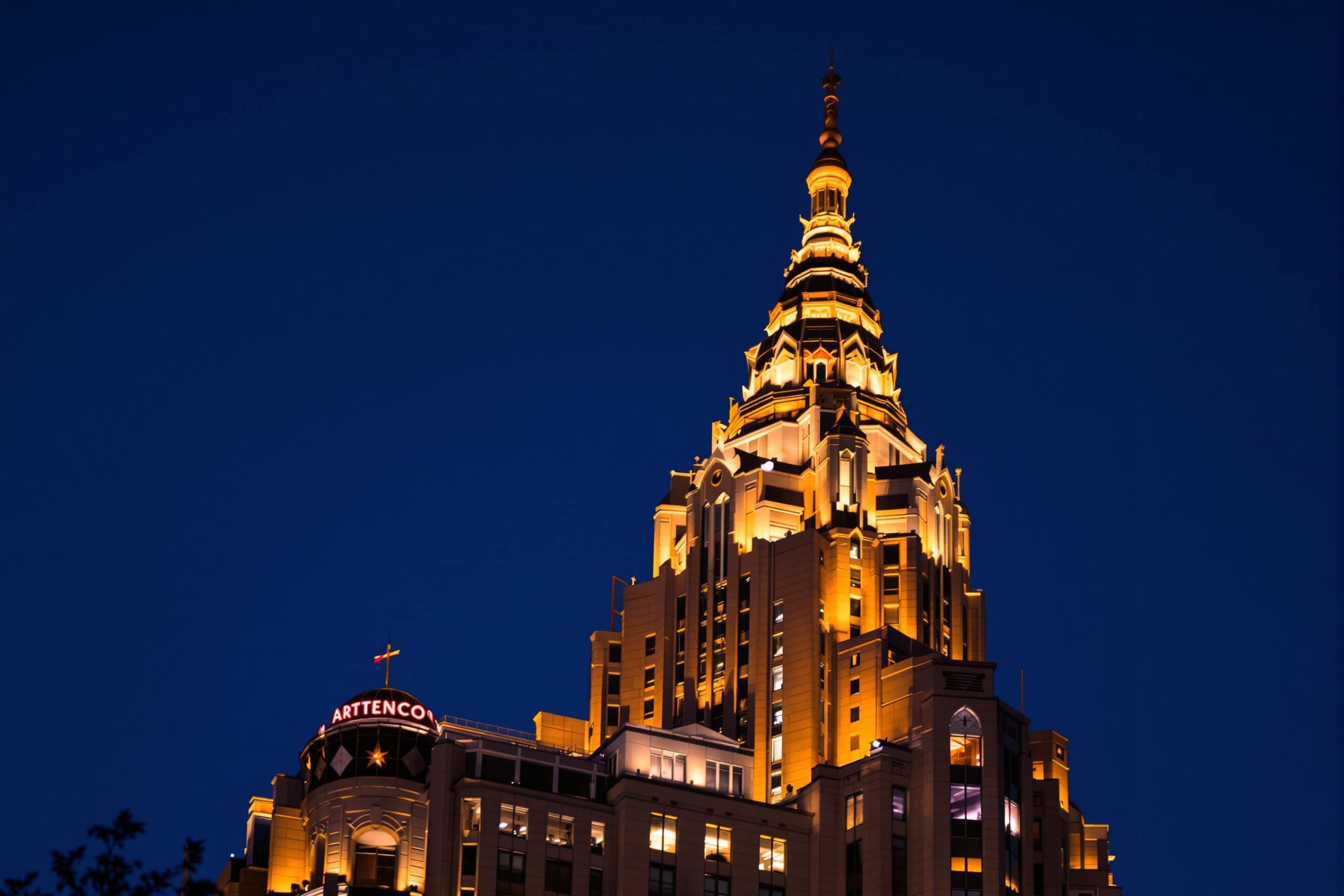 Capture the timeless elegance of Art Deco architecture in this stunning twilight shot of a majestic skyscraper. The building's stepped silhouette and intricate geometric patterns are accentuated by warm, golden lighting, creating a captivating interplay of light and shadow against the deep blue evening sky.