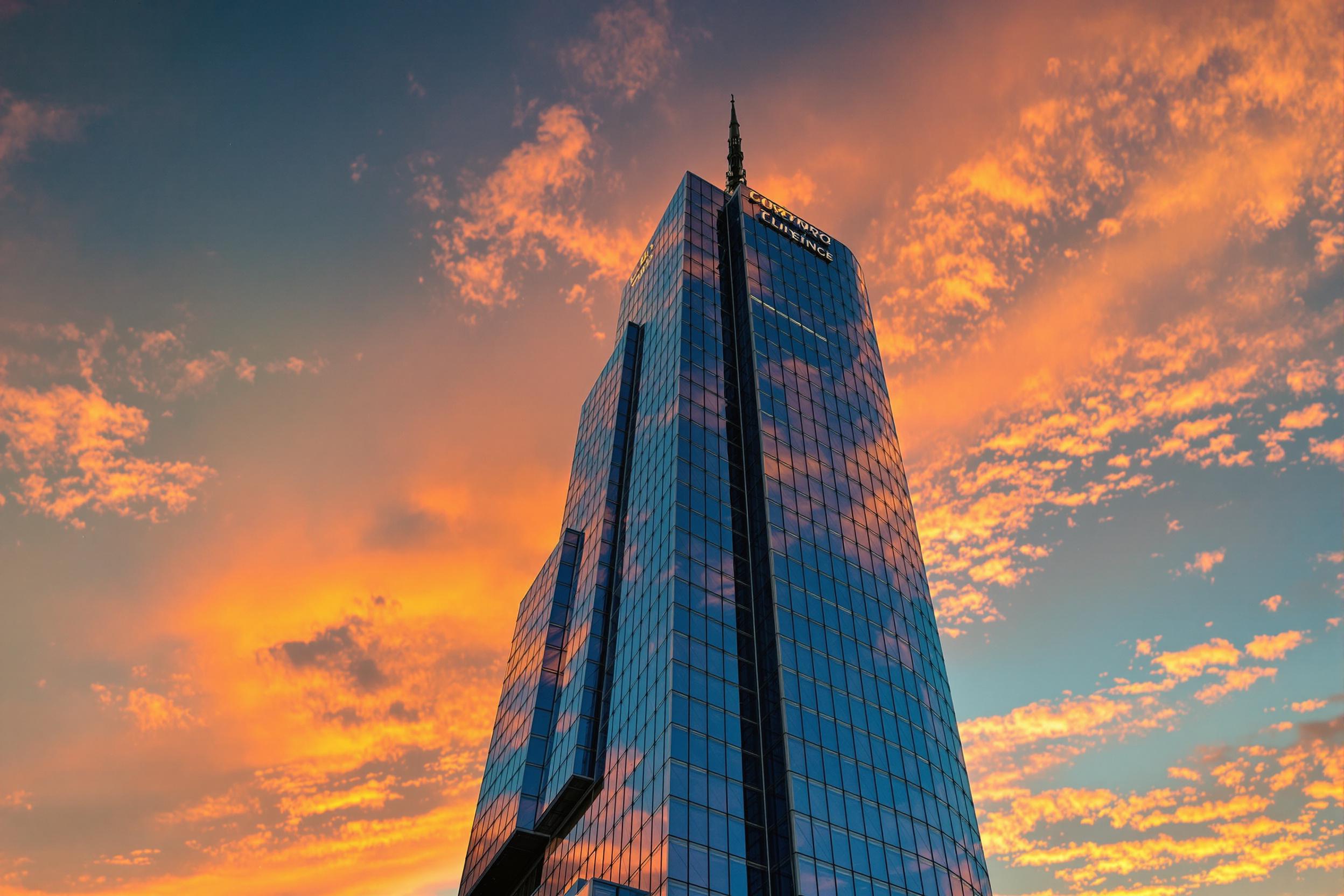 Explore the beauty of modern architecture with this stunning photograph showcasing a sleek skyscraper against a vibrant sunset. The geometric lines and reflective glass create a captivating visual, while the warm hues of the sky add a dramatic touch. Perfect for articles on urban design and contemporary architecture.