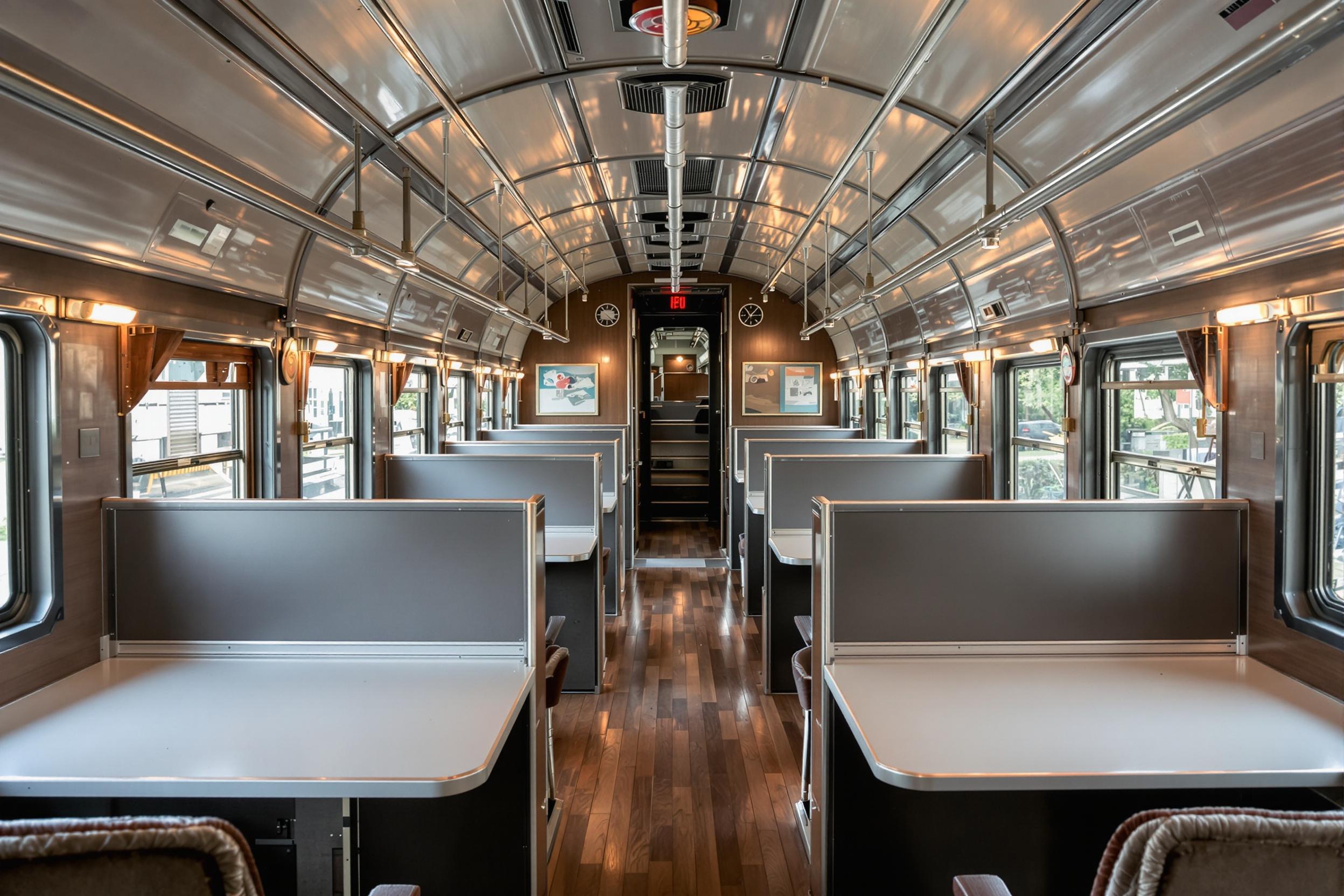 Discover a unique business environment inside a renovated vintage train car. This innovative coworking space blends nostalgia with modern functionality, featuring sleek workstations, warm lighting, and original train details. The scene captures the essence of creative workplace solutions and adaptive reuse in business.