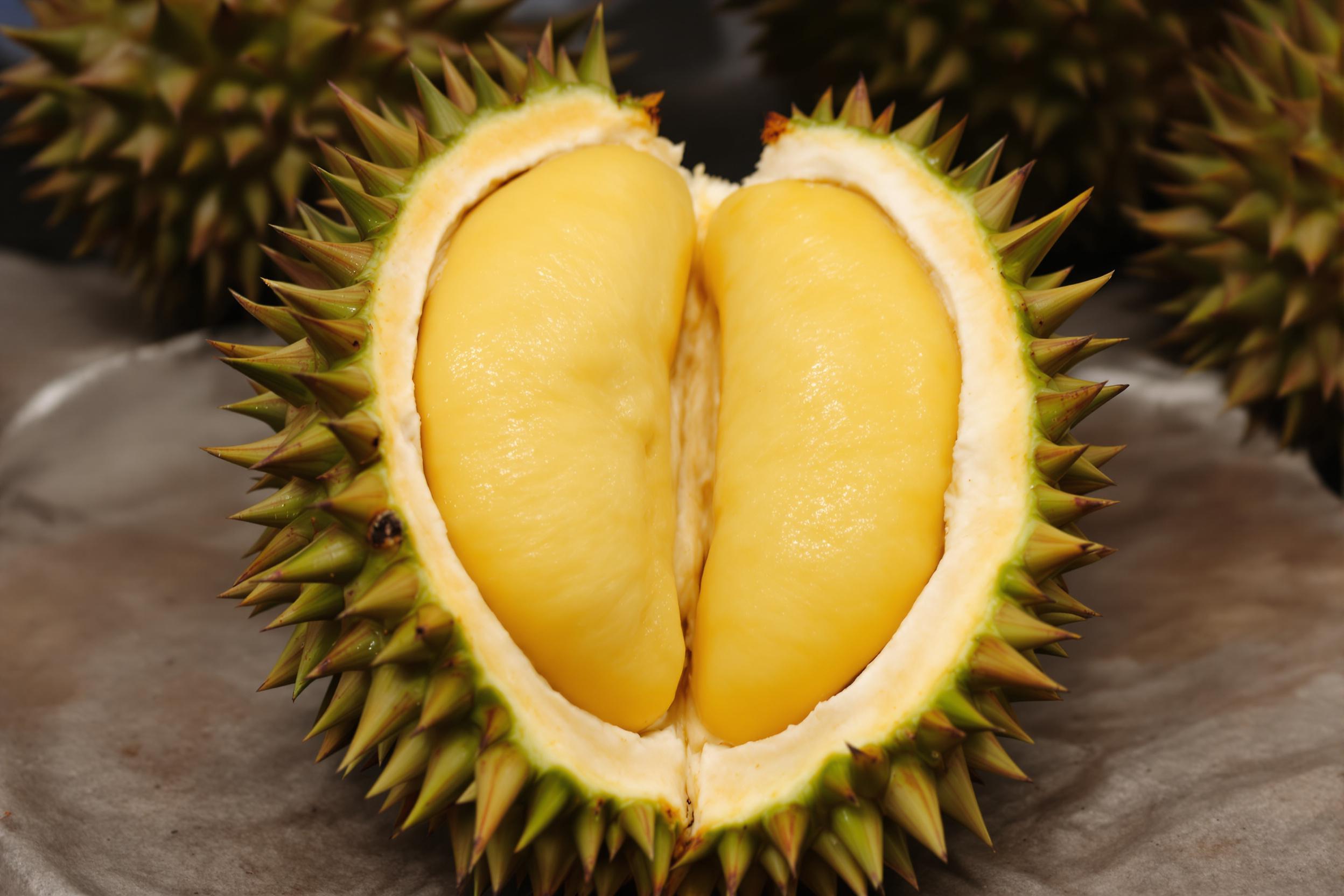 Explore the controversial king of fruits in this captivating image of a durian tasting experience. A halved durian reveals its creamy, pale yellow flesh against its spiky green exterior, inviting viewers to embrace its unique aroma and flavor.