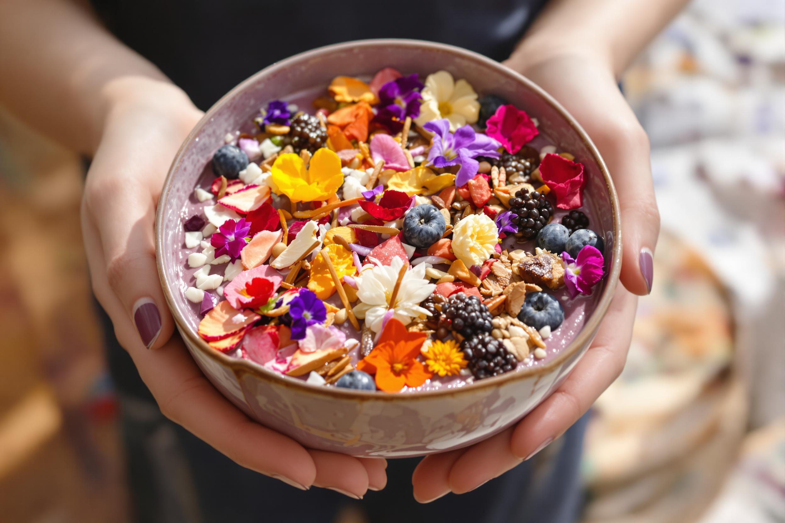 A beautifully crafted acai bowl adorned with a rainbow of toppings including edible flowers, creating a visually stunning and nutritious breakfast. Captured in soft morning light, this image showcases the artistry of healthy eating.