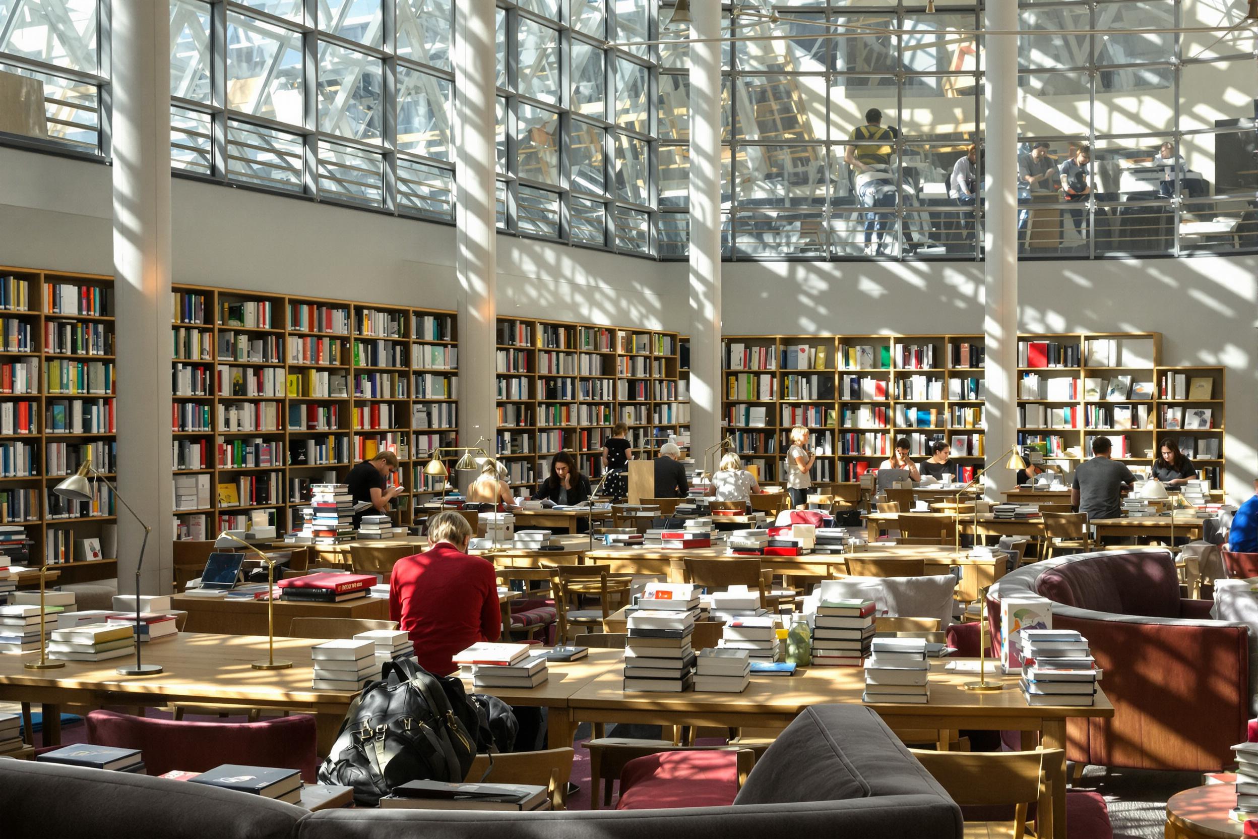 Inside a modern library, sunlight streams through expansive windows, illuminating individuals engrossed in their books. Wooden tables are scattered about, adorned with neatly stacked novels and cozy reading lamps. Vividly colored book spines create a striking backdrop, while plush seating areas invite quiet contemplation.