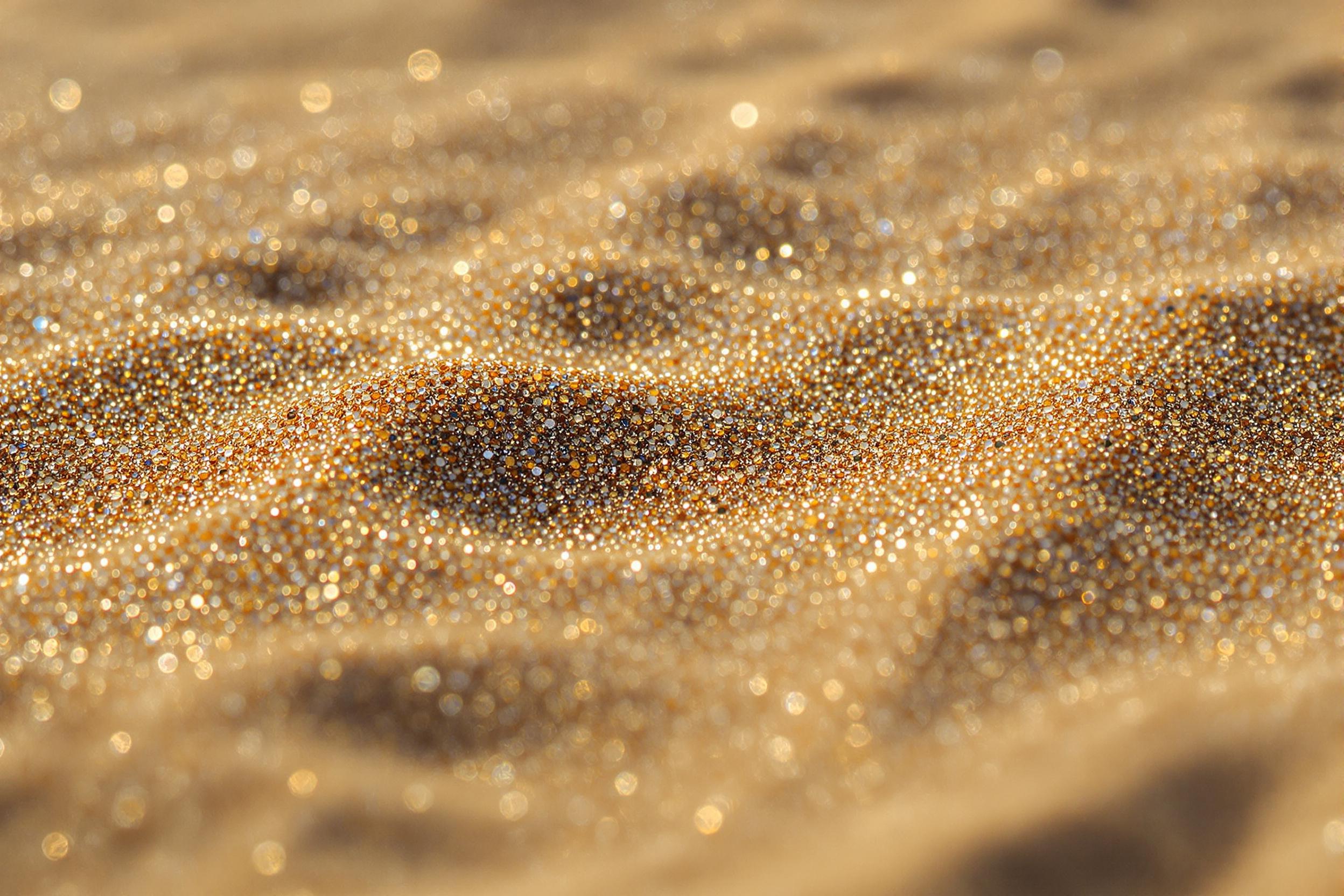 An extreme macro captures sunlit sand grains glistening in intricate detail on a pristine shoreline. Each tiny particle reflects warm golden tones, interspersed with subtle silvery specks. Harsh mid-morning sunlight creates natural shadows that emphasize the undulating micro-texture of the sand, transforming it into a mesmerizing geometric tapestry.