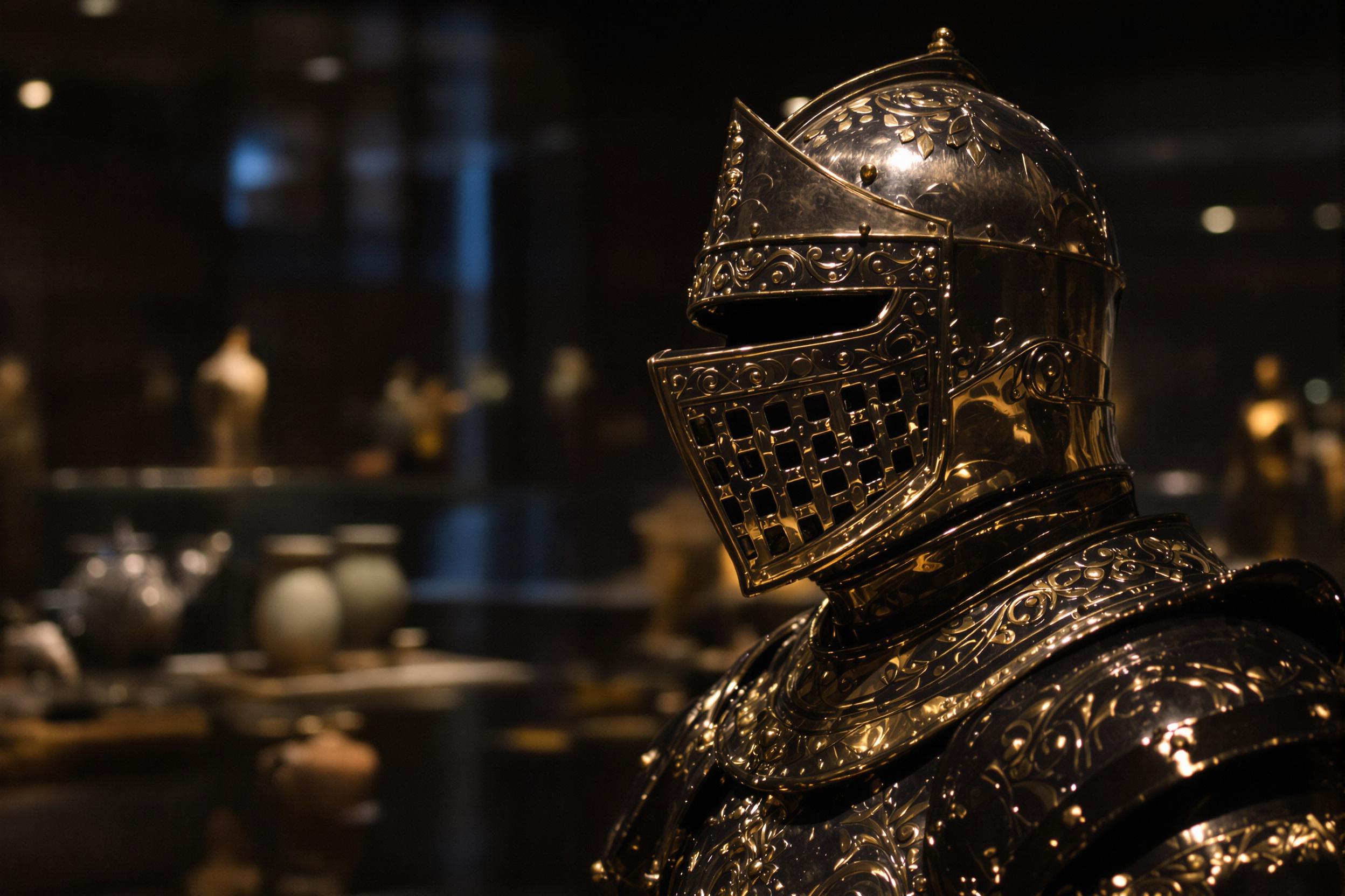 This composition features a medium close-up of an ornately detailed piece of medieval knight's armor displayed in a dimly lit museum exhibit. Its polished steel surface glimmers under controlled directional lighting, emphasizing intricate engravings and fine craftsmanship. In the background, softly blurred artifacts evoke a sense of rich history and preservation.