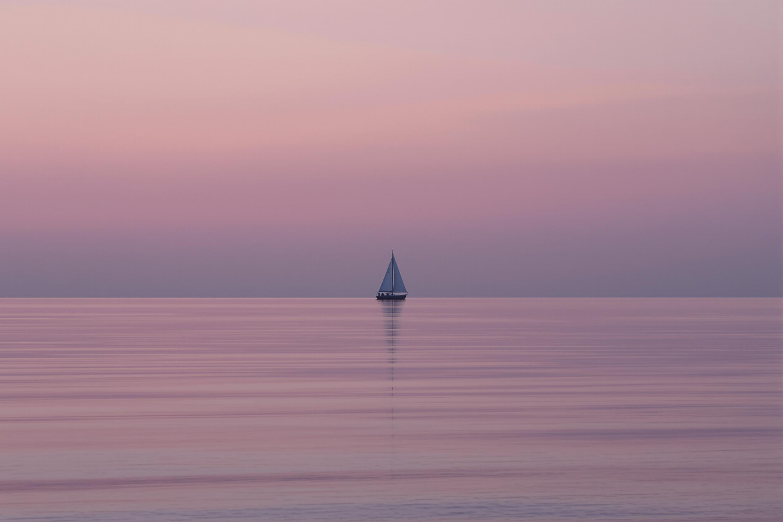 A solitary sailboat silhouette against a gradient twilight sky, reflecting on calm waters. This minimalist seascape captures tranquility and vastness, emphasizing negative space and a muted color palette for a serene, contemplative atmosphere.