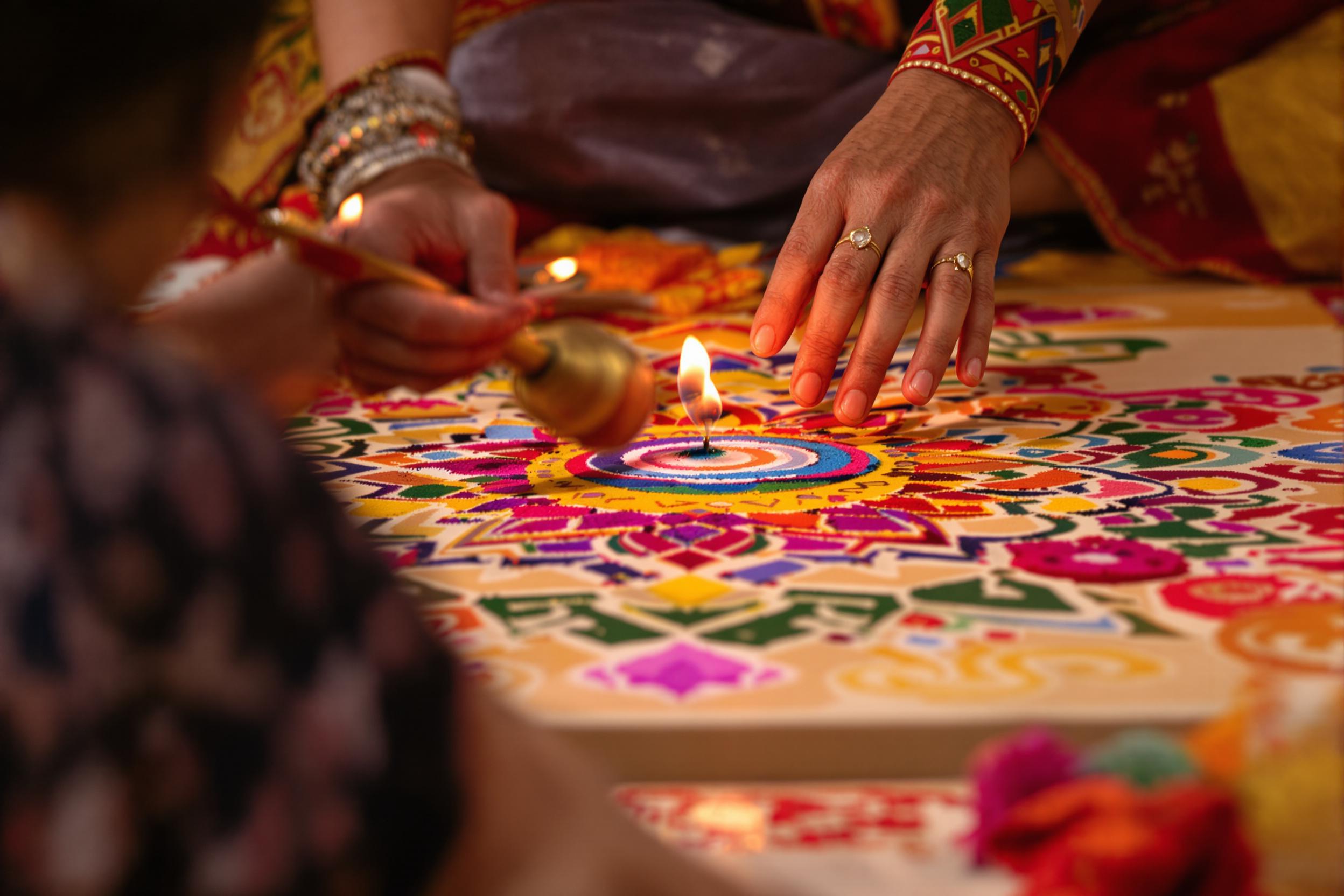 Close focus captures patient hands assembling an intricate sand mandala with vibrant pigments. Gentle lighting accentuates finely detailed patterns as colorful grains of sand form geometric designs atop a flat platform. Cultural motifs subtly decorate the surrounding, enriching the spiritual atmosphere.