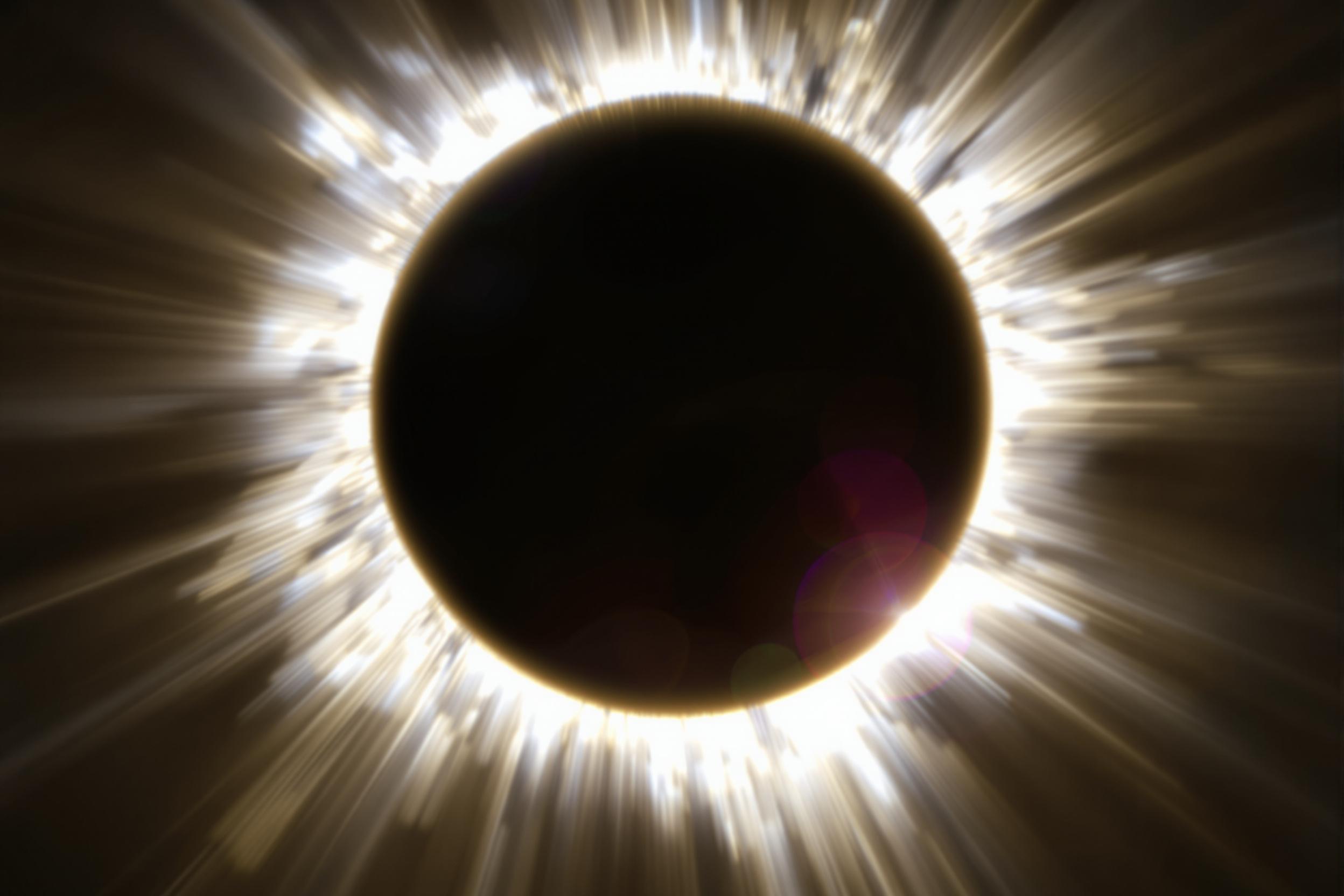 Stunning capture of a total solar eclipse at the moment of the diamond ring effect. The sun's corona forms a brilliant halo around the moon's dark silhouette, with a dazzling burst of light emerging from behind the lunar limb.