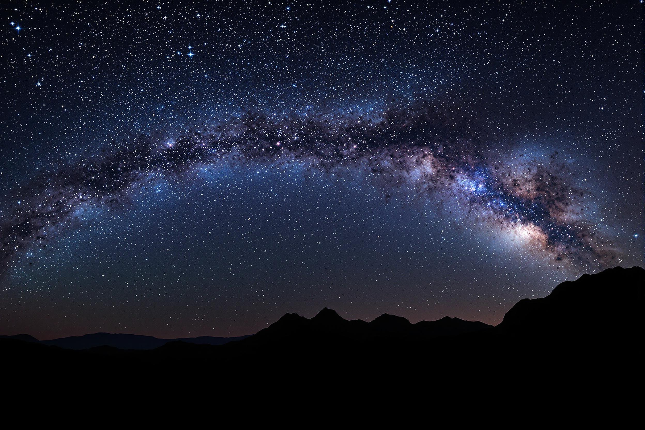 Breathtaking view of the Milky Way galaxy arching over a silhouetted mountain range. Vibrant stars and cosmic dust illuminate the night sky, creating a mesmerizing celestial landscape. Perfect for astronomy enthusiasts and nature lovers.