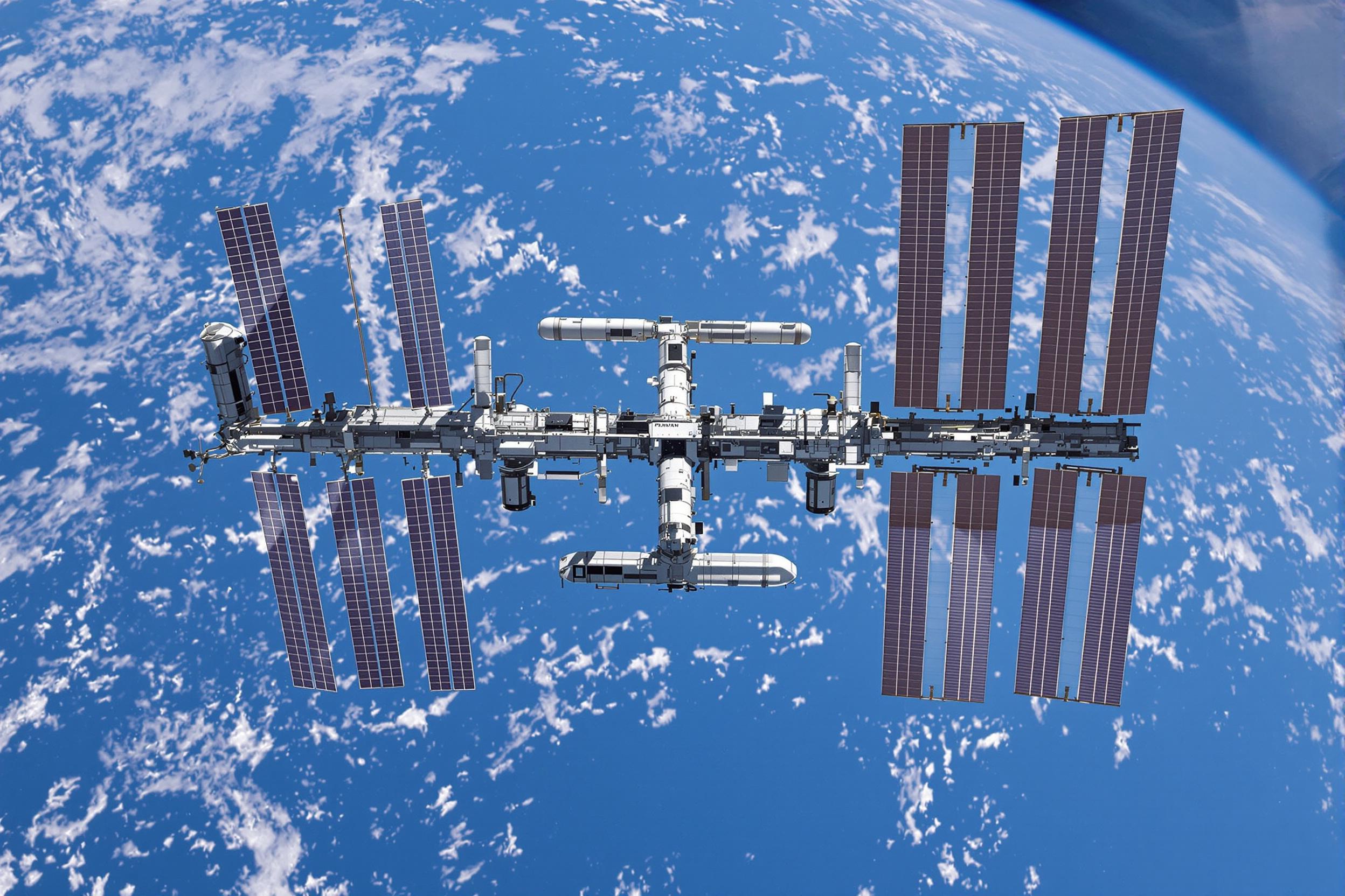 High-resolution image of the International Space Station orbiting Earth. The sleek structure of the ISS contrasts against the blue planet below, with sunlight glinting off solar panels. Captures the marvel of human achievement in space exploration.