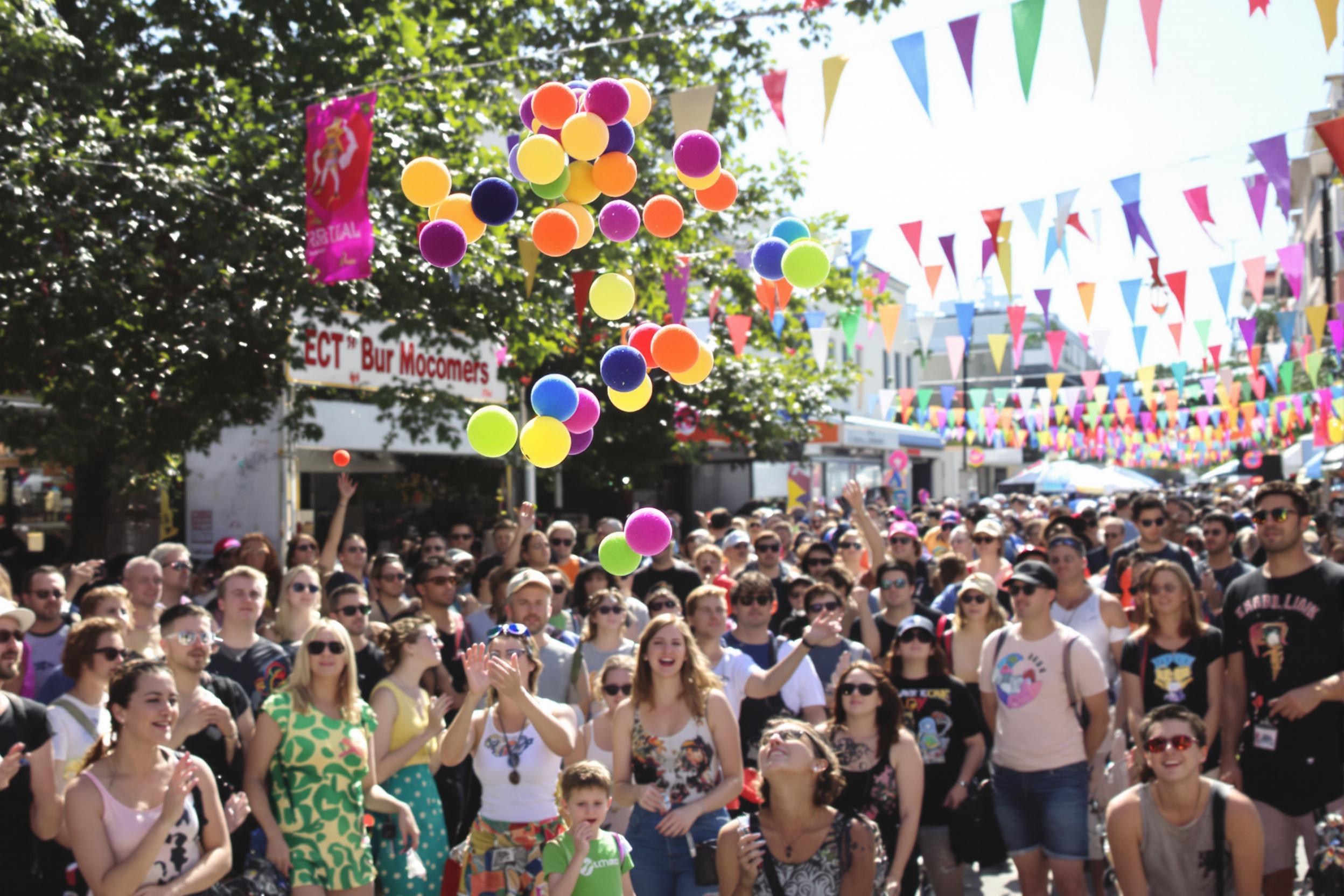 A dynamic street performer captivates a crowd as they juggle a series of vibrant, multicolored balls against the backdrop of a bustling festival. Laughter and excitement fill the air, while spectators of all ages watch intently. The sun casts bright light, causing the balls to gleam. Colorful banners flutter in the gentle breeze, adding to the festive atmosphere.