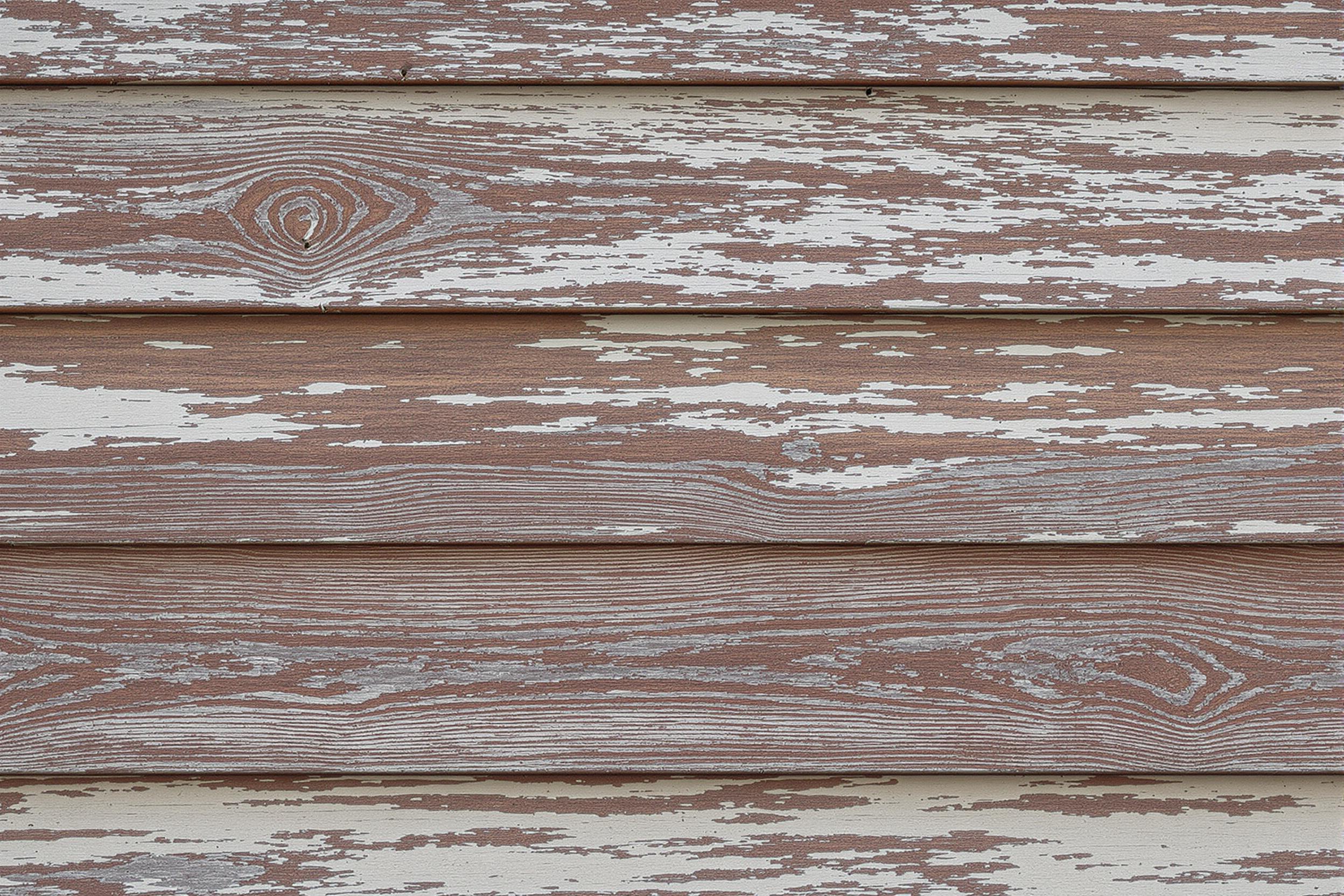 Close-up of weathered barn wood siding, showcasing layers of peeling paint and rich wood grain. Soft, diffused lighting highlights the texture and patina of decades of exposure, creating a visually compelling study of time's passage on rural architecture.