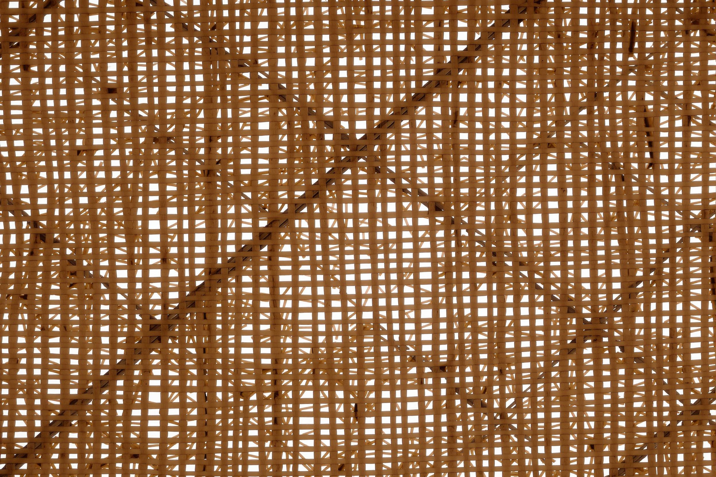 Close-up of intricate bamboo weaving used in traditional Asian architecture. Natural, sustainable material creates a mesmerizing geometric pattern of light and shadow, showcasing eco-friendly design elements.