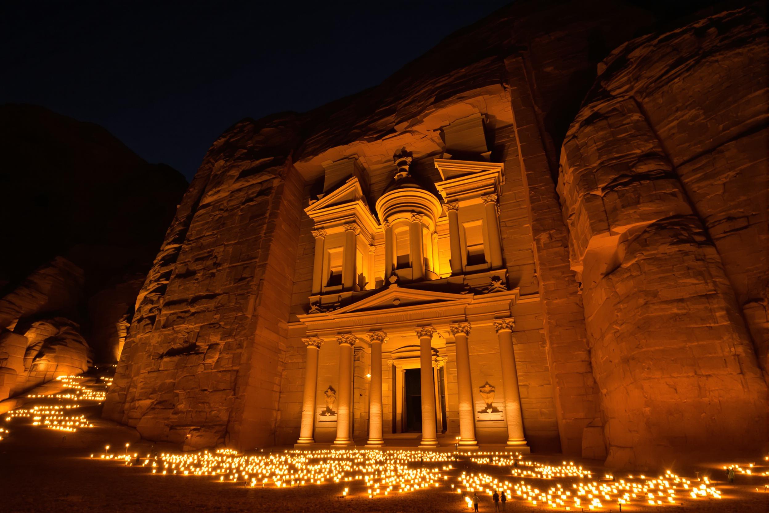 Experience the enchanting beauty of Petra's Treasury at night, illuminated by hundreds of flickering candles. This captivating scene showcases the intricate facade of the ancient Nabataean monument bathed in warm, golden light, creating a magical atmosphere that transports viewers to a bygone era.