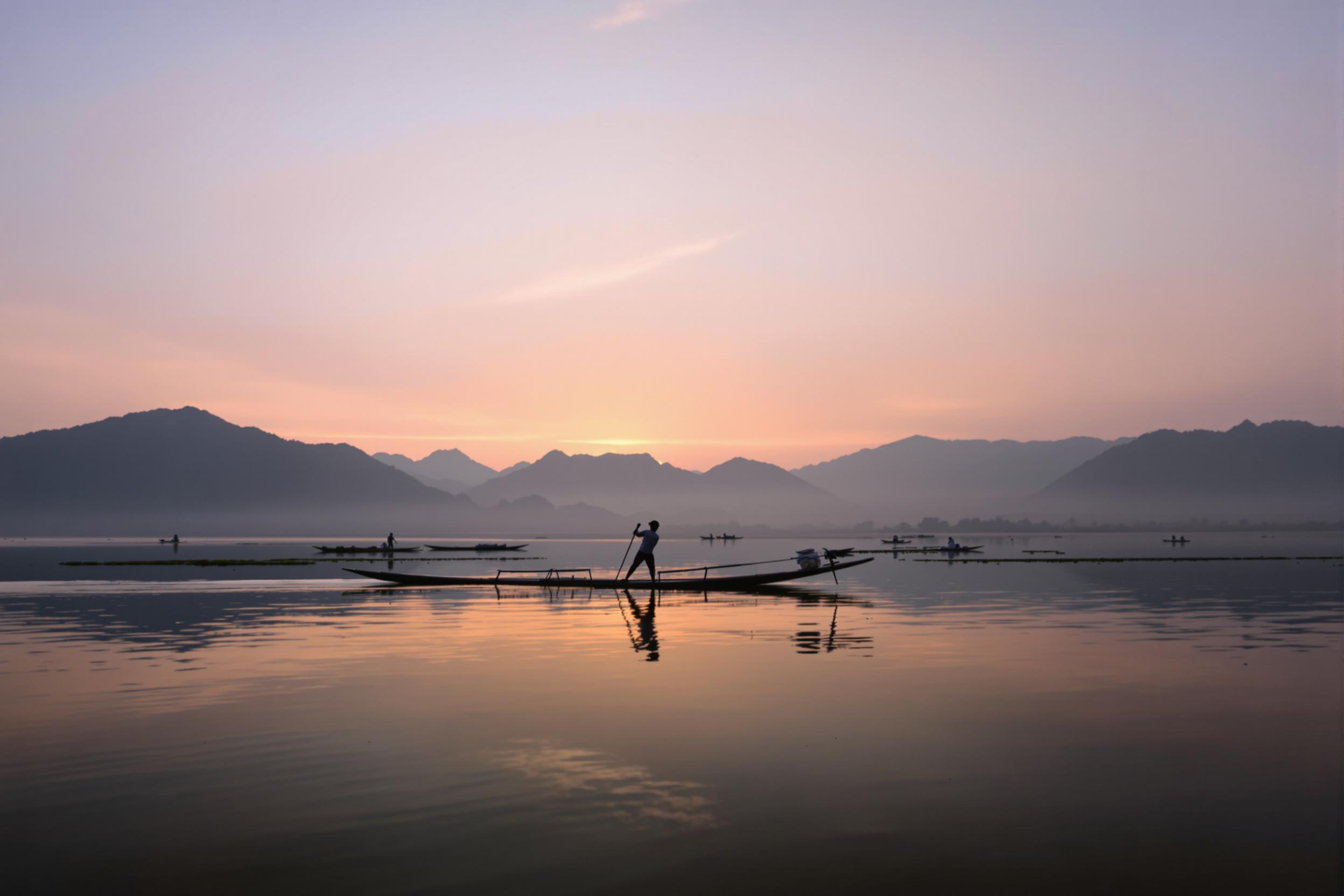 Experience the serene beauty of Inle Lake at dawn. A lone fisherman, silhouetted against the pastel sky, demonstrates the traditional one-legged rowing technique. Misty mountains frame the scene, reflecting perfectly in the glassy water.